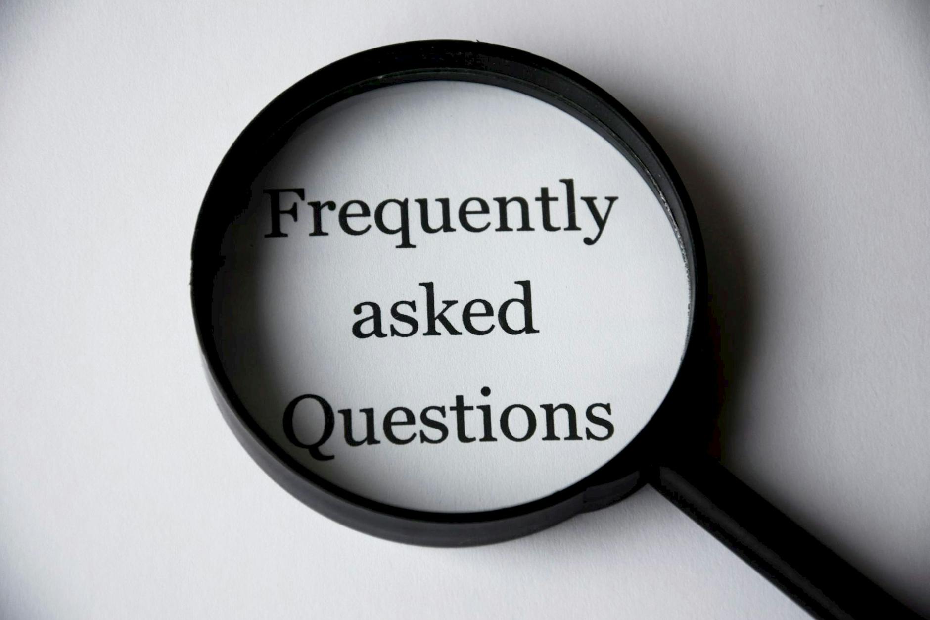 black magnifying glass with frequently asked questions showing through