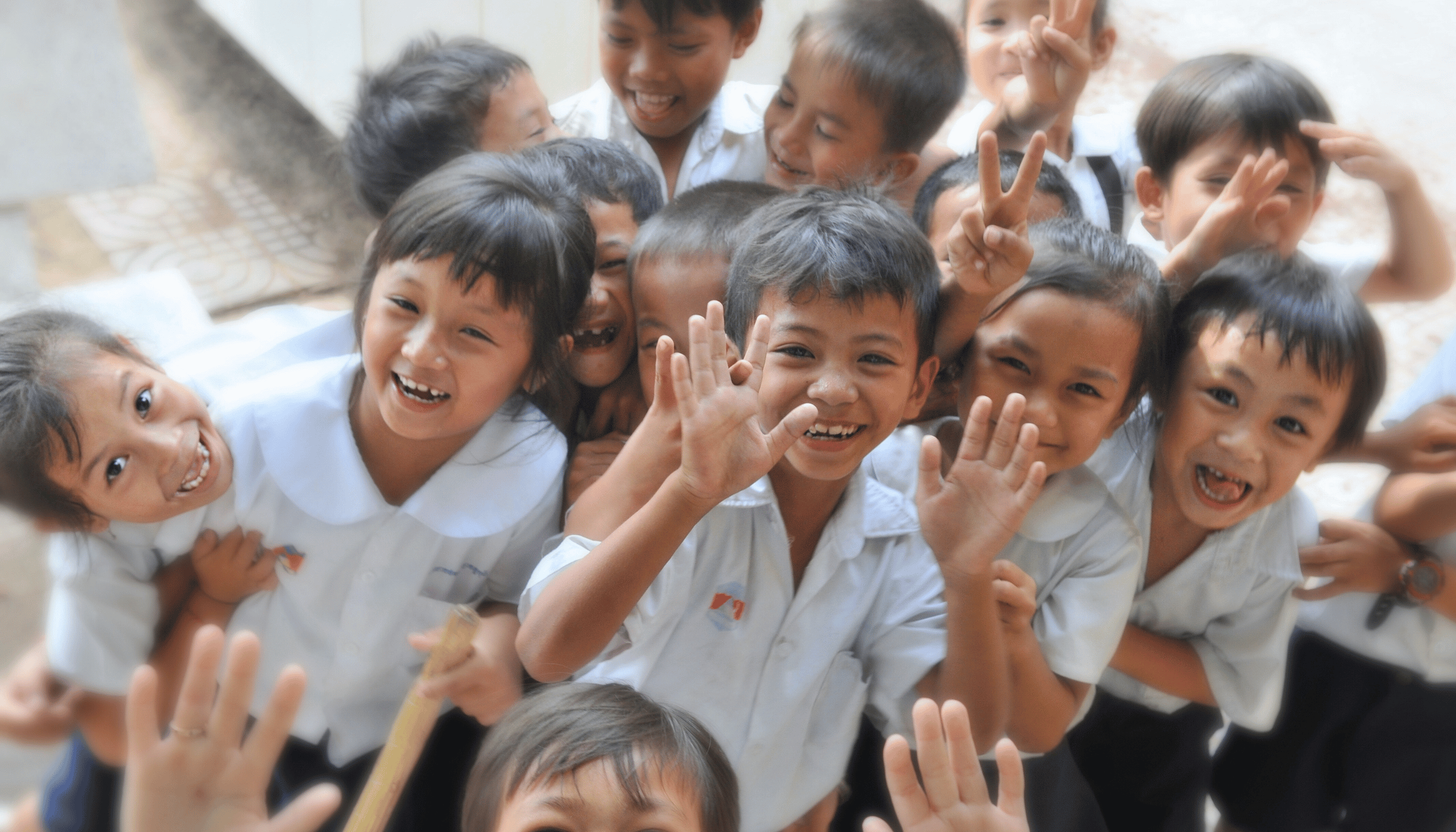 bunch of international school children waving to the camera