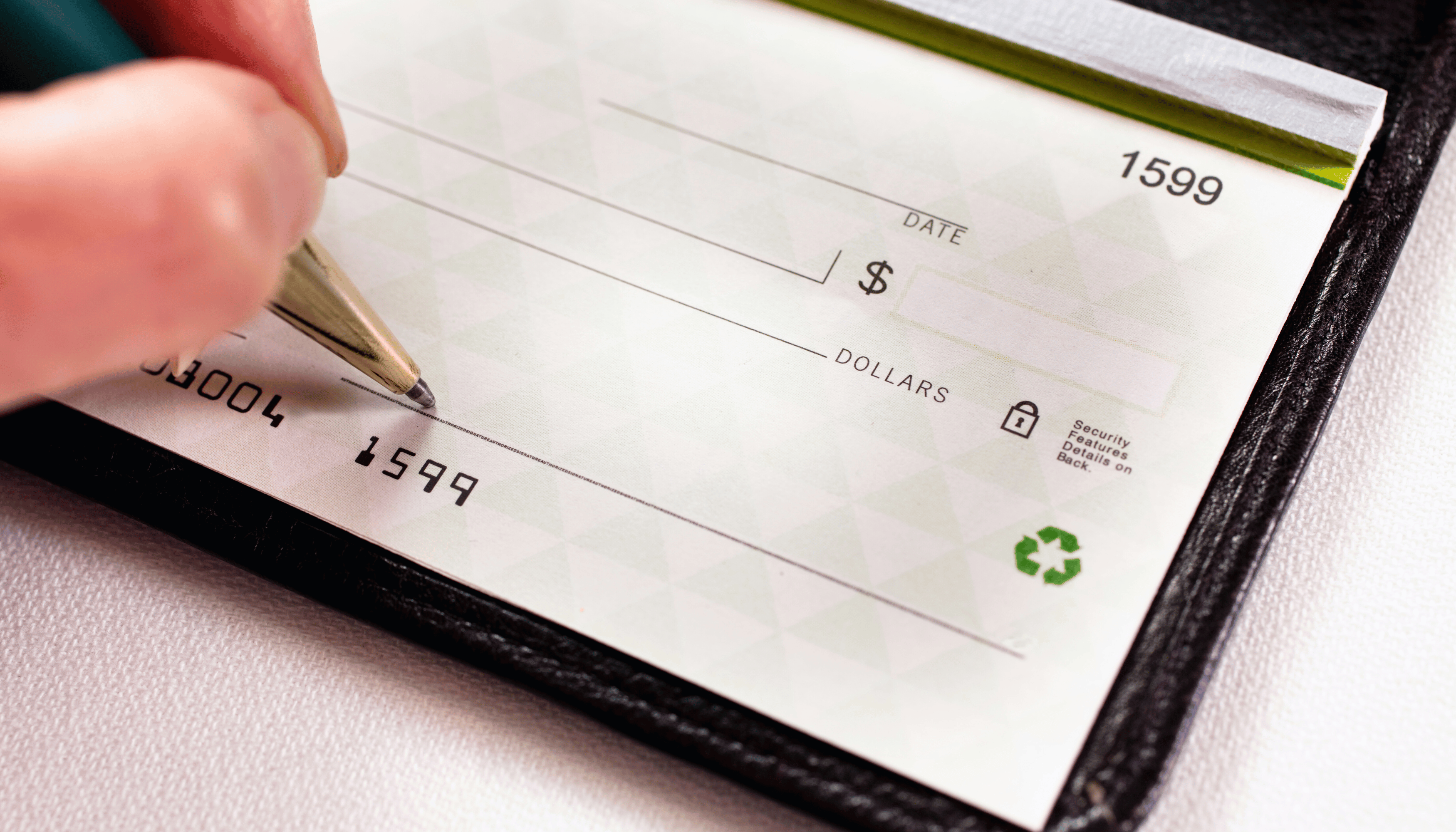 Close-up of a person writing on a traditional bank check, representing financial transactions or payments using paper drafts.