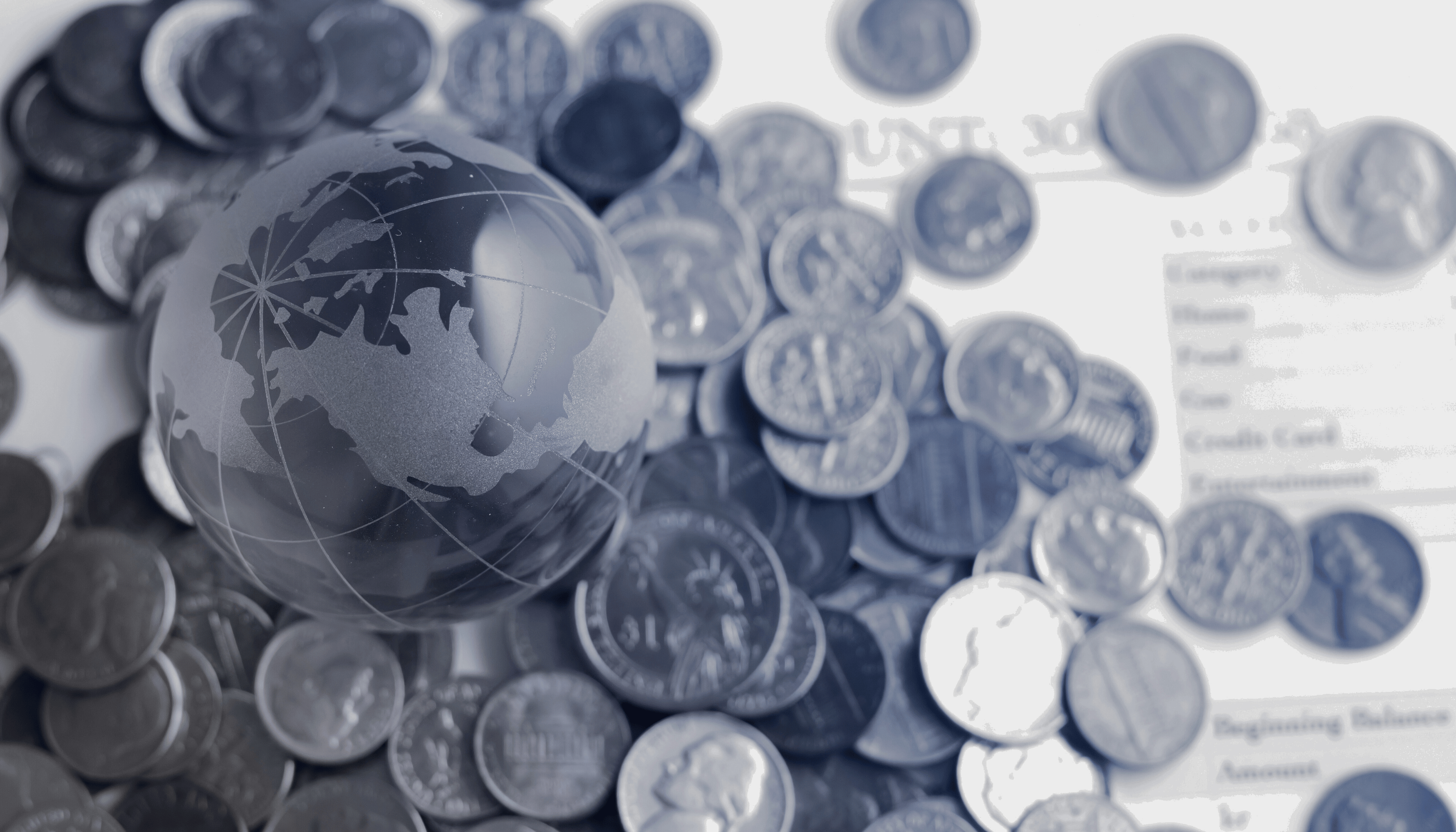 Image of a transparent globe placed over various coins, symbolizing global financial transactions and currency exchange, ideal for business transfers and international payments.