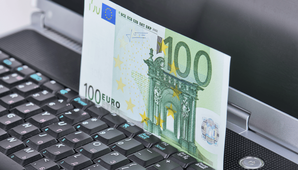Close-up of a 100 Euro banknote standing on a laptop keyboard, representing online currency echange or digital finance.